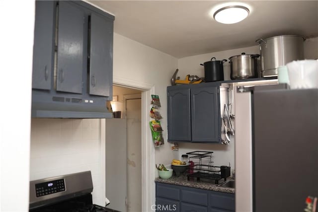 kitchen featuring decorative backsplash, gray cabinets, under cabinet range hood, and stainless steel stove
