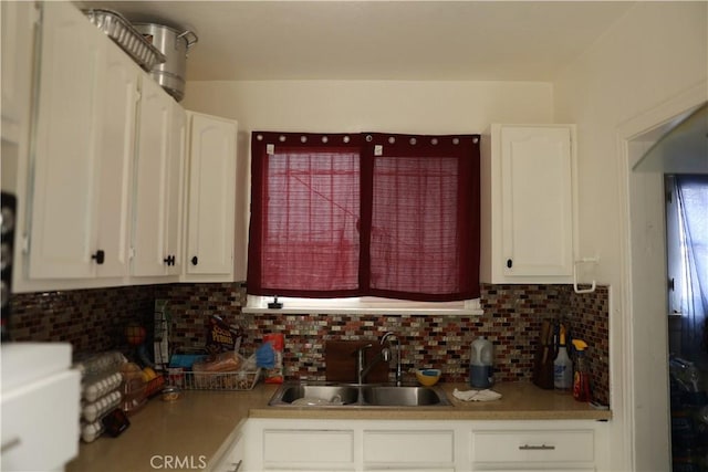 kitchen featuring light countertops, white cabinetry, a sink, and tasteful backsplash