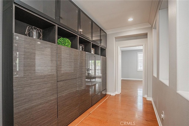 hall with baseboards, ornamental molding, and light wood-type flooring