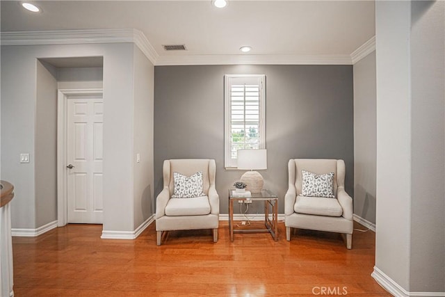 living area featuring light wood-style floors, baseboards, and crown molding