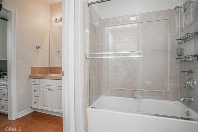 full bath with bath / shower combo with glass door, baseboards, vanity, and wood finished floors