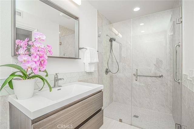 bathroom featuring vanity, wainscoting, a shower stall, and tile walls