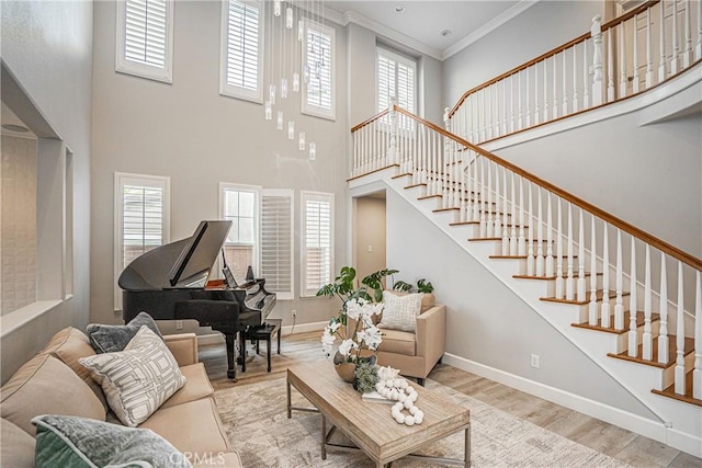 living area with stairway, baseboards, a high ceiling, and wood finished floors