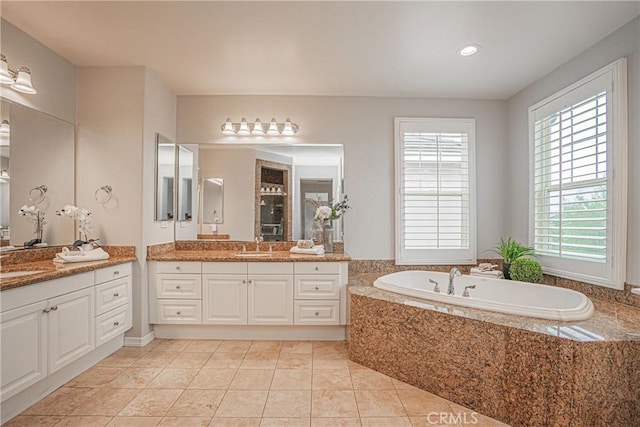 bathroom with tile patterned floors, two vanities, a sink, and a bath