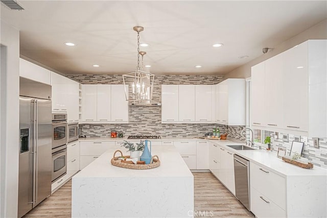 kitchen with a sink, light wood-style flooring, a center island, stainless steel appliances, and visible vents