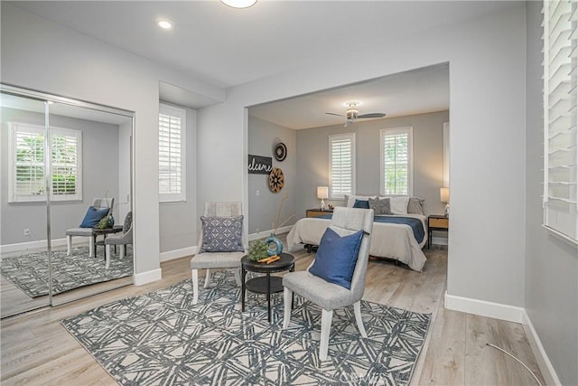 interior space with a ceiling fan, baseboards, and light wood-style flooring