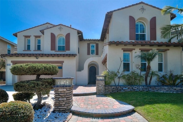 mediterranean / spanish home with a tile roof, a front yard, and stucco siding