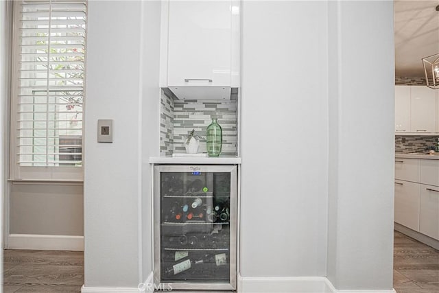 details featuring baseboards, tasteful backsplash, wood finished floors, and wine cooler