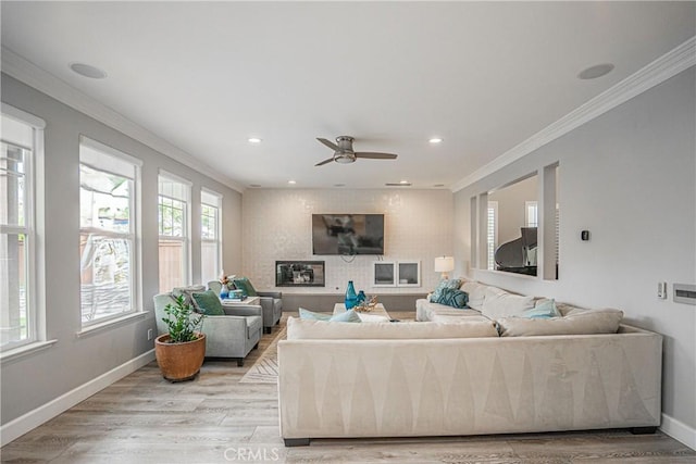 living area with ceiling fan, ornamental molding, baseboards, and light wood-style floors