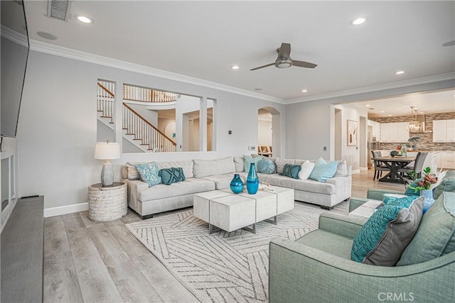 living room with ceiling fan, arched walkways, stairs, light wood finished floors, and recessed lighting