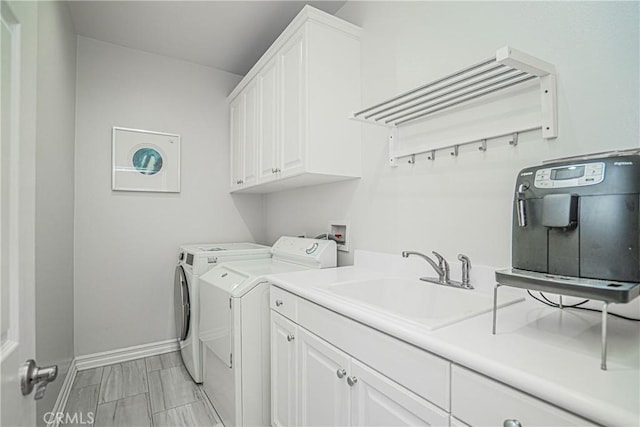 clothes washing area featuring a sink, baseboards, cabinet space, and washing machine and clothes dryer