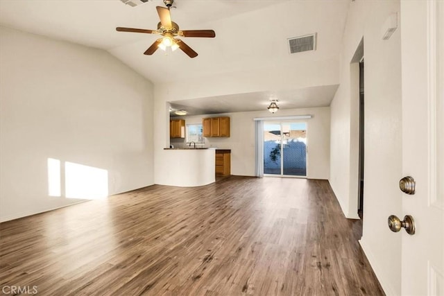 unfurnished living room with visible vents, a sink, a ceiling fan, dark wood finished floors, and vaulted ceiling