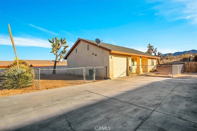 view of home's exterior featuring fence, an attached garage, stucco siding, a gate, and concrete driveway
