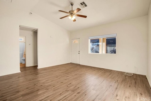 empty room featuring plenty of natural light, ceiling fan, wood finished floors, and lofted ceiling