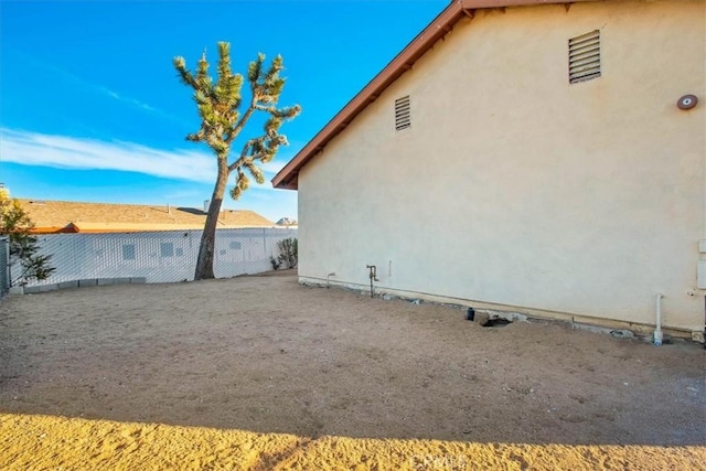 view of side of property with fence and stucco siding