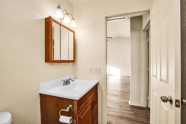 half bath featuring vanity, wood finished floors, and toilet