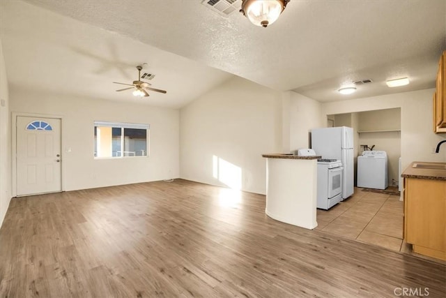 kitchen with a sink, dark countertops, washer / clothes dryer, light wood-type flooring, and a ceiling fan