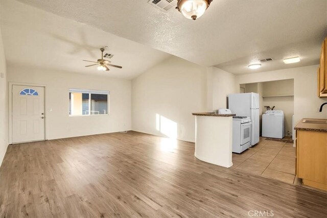 60803 Division St, Joshua Tree, CA 92252 - kitchen featuring washer / dryer, ceiling fan, dark countertops, white appliances, and light wood-type flooring
