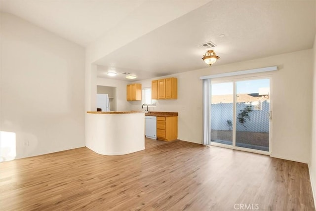 kitchen with a sink, white appliances, light wood-style flooring, and a wealth of natural light