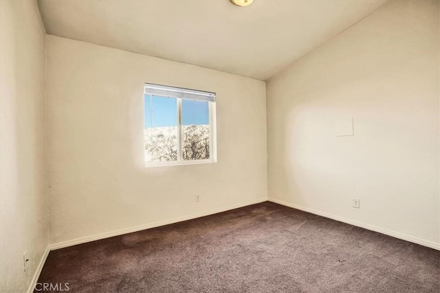 spare room featuring baseboards and dark colored carpet