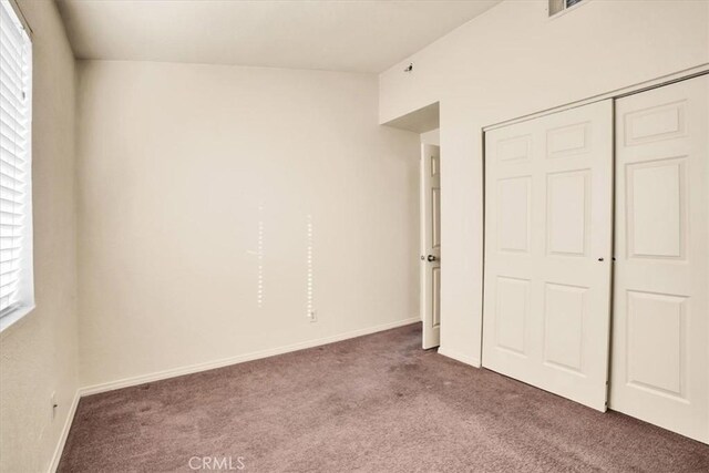 unfurnished bedroom with a closet, baseboards, and carpet flooring