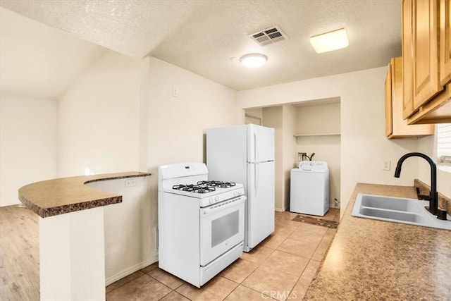 kitchen with a sink, white appliances, a textured ceiling, washer / dryer, and visible vents