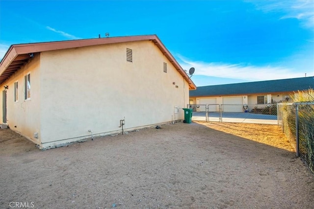 view of side of home with fence, stucco siding, and a garage