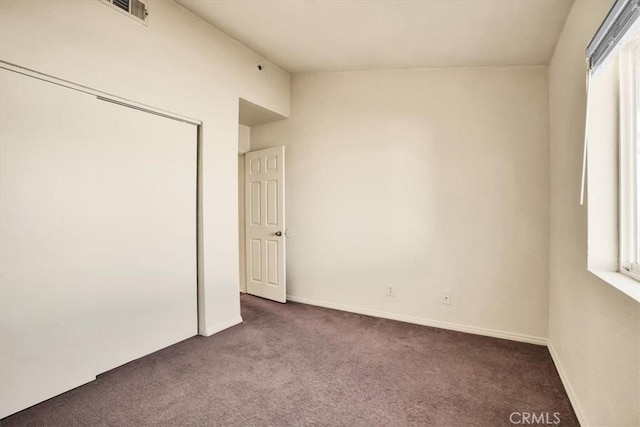 unfurnished bedroom featuring carpet floors, baseboards, a closet, and visible vents