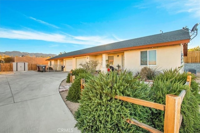 ranch-style home with fence, a garage, stucco siding, concrete driveway, and central air condition unit