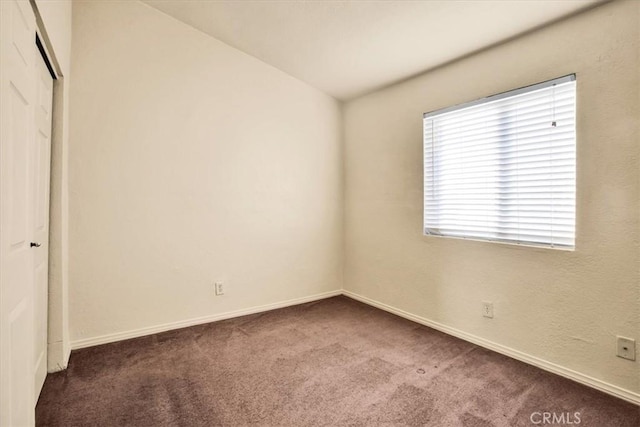 unfurnished bedroom with dark colored carpet, baseboards, and a closet