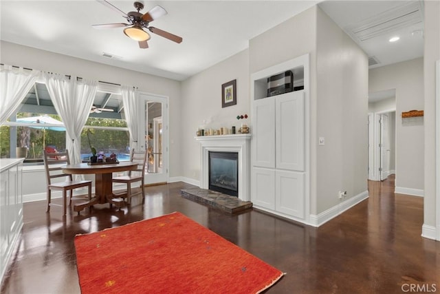 living area with a glass covered fireplace, concrete floors, a ceiling fan, baseboards, and visible vents