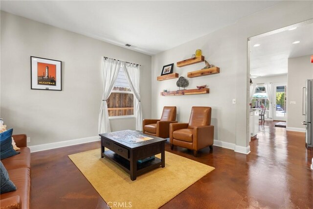 living room featuring recessed lighting, baseboards, and concrete floors