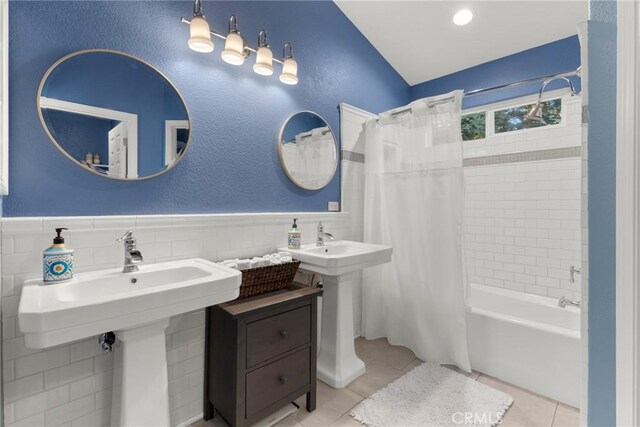 full bathroom with shower / bath combination with curtain, tile walls, wainscoting, vaulted ceiling, and tile patterned floors