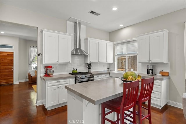 kitchen with decorative backsplash, recessed lighting, wall chimney exhaust hood, a sink, and high end range