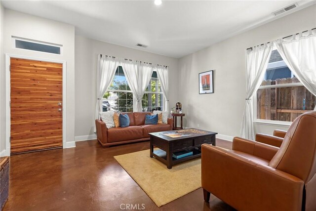 living room featuring baseboards, concrete flooring, and visible vents