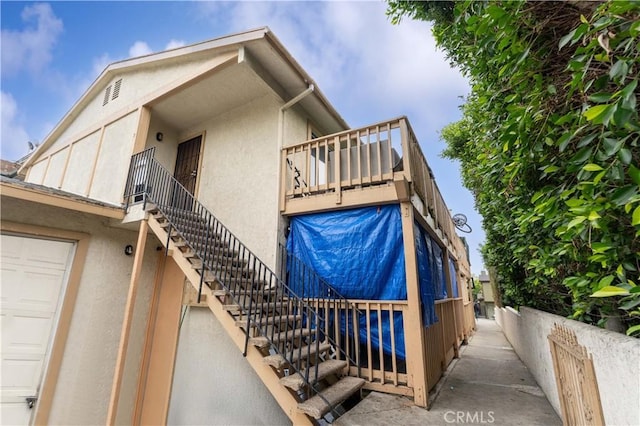 view of side of home featuring stucco siding and stairway