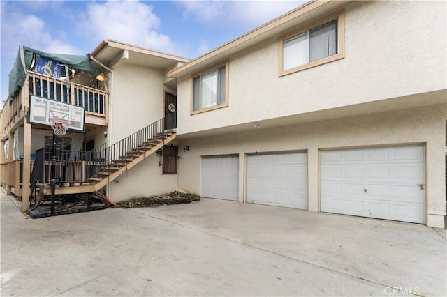 exterior space with concrete driveway, an attached garage, stairs, and stucco siding