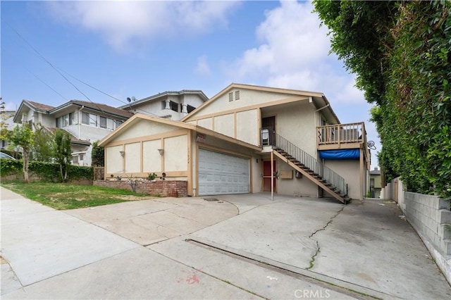 view of front of property featuring stairway, a garage, concrete driveway, and stucco siding