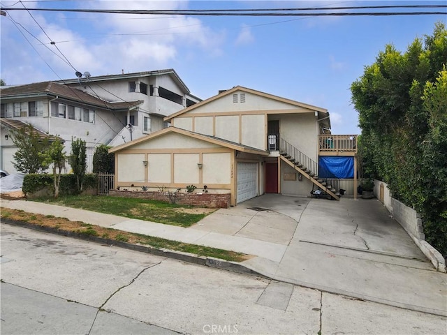 view of front of home featuring fence, a garage, stucco siding, stairway, and driveway