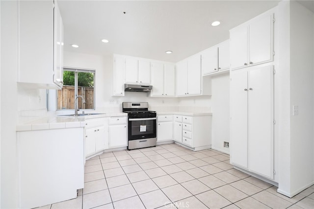 kitchen with recessed lighting, a sink, under cabinet range hood, and gas stove