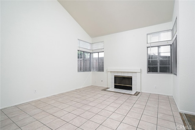 unfurnished living room featuring baseboards, high vaulted ceiling, and a tile fireplace