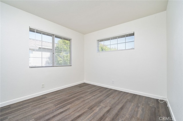 unfurnished room featuring baseboards and dark wood-style floors