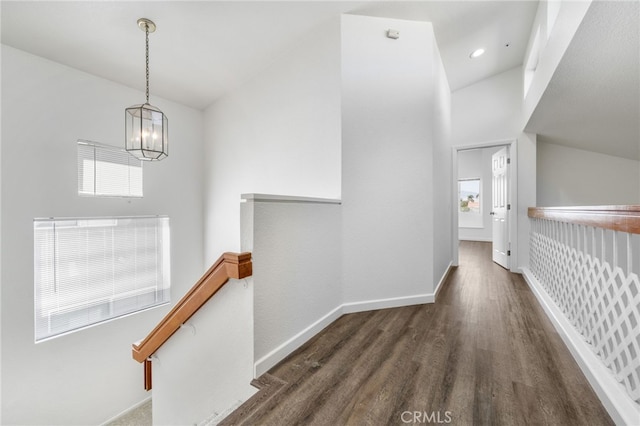 corridor featuring a notable chandelier, baseboards, an upstairs landing, wood finished floors, and vaulted ceiling