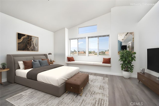 bedroom featuring baseboards, wood finished floors, and high vaulted ceiling