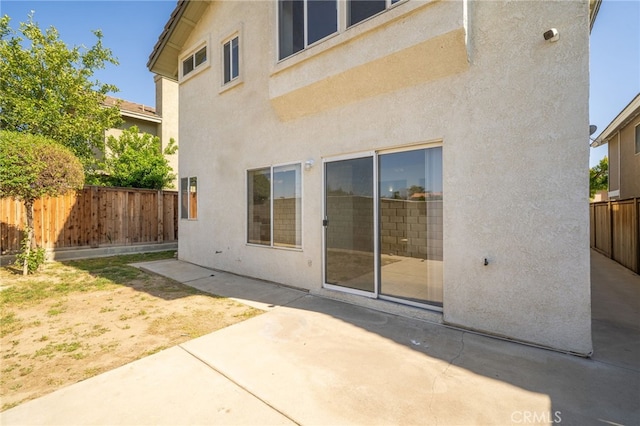 rear view of house featuring a fenced backyard, a patio area, and stucco siding