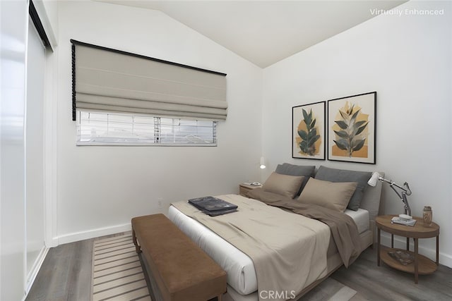 bedroom featuring baseboards, wood finished floors, and lofted ceiling