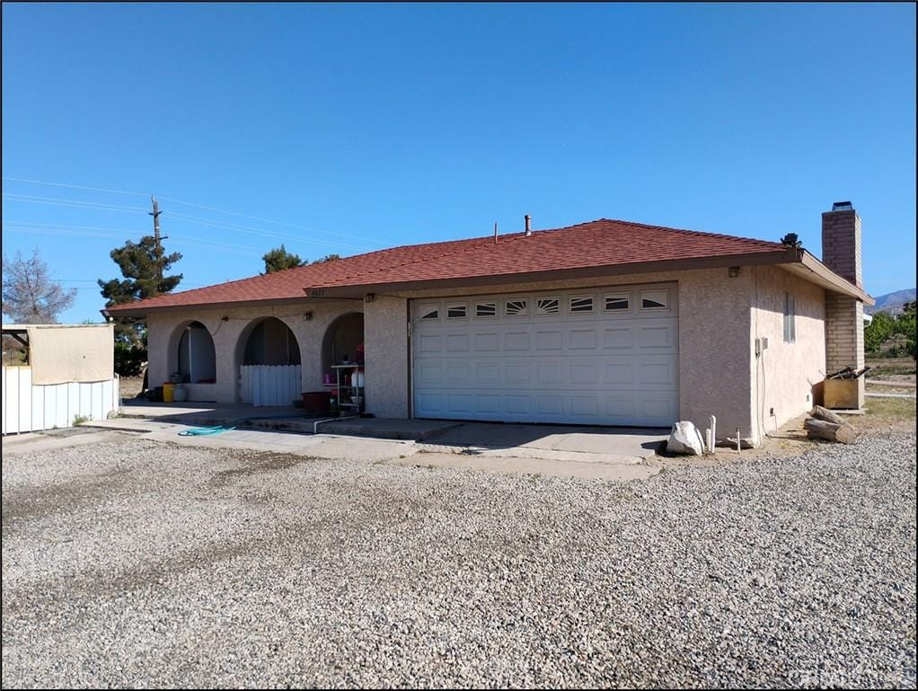 4077 Amador Rd, Phelan, CA 92371 - ranch-style home featuring a garage, driveway, a chimney, and stucco siding