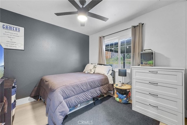 bedroom with ceiling fan, wood finished floors, and baseboards