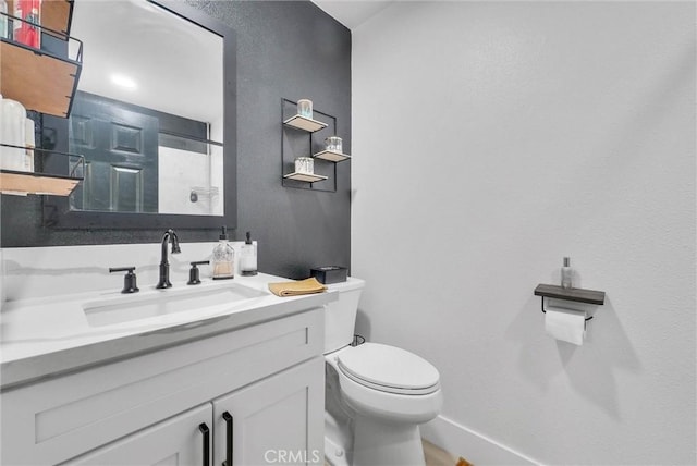 bathroom featuring baseboards, toilet, and vanity