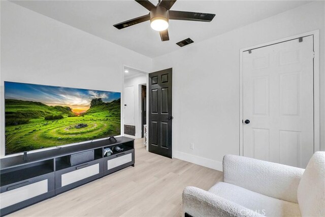 living area with light wood-style flooring, a ceiling fan, and baseboards